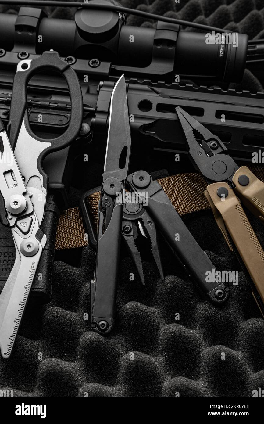 Modern multitool with many tools. A portable multitasking military tool lies next to the weapon