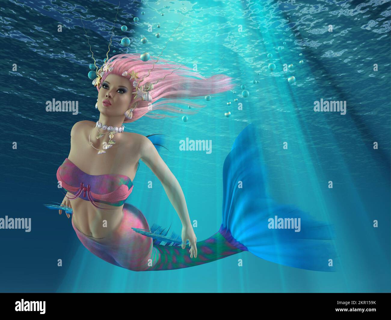 Turmaline the Mermaid swims underwater through rays of sunshine along with blue bubbles. Stock Photo