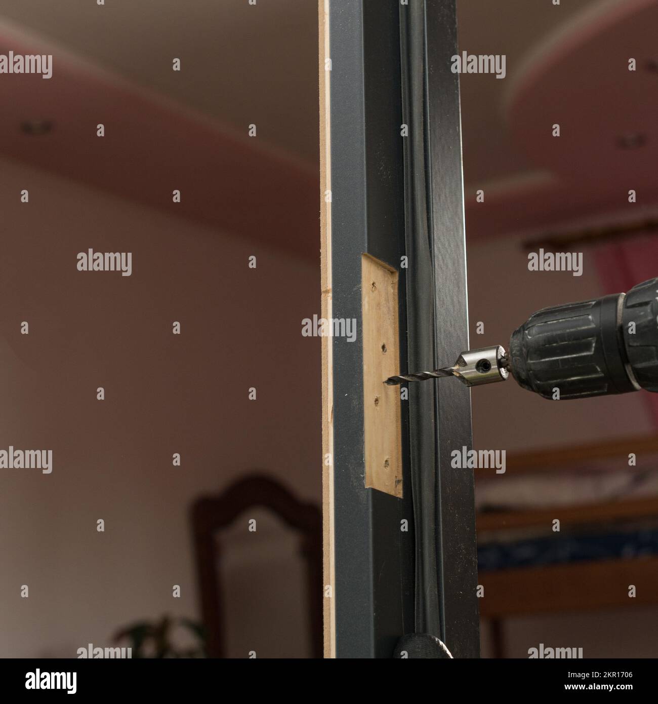 In the door frame, the master drills a hole for further attachment to