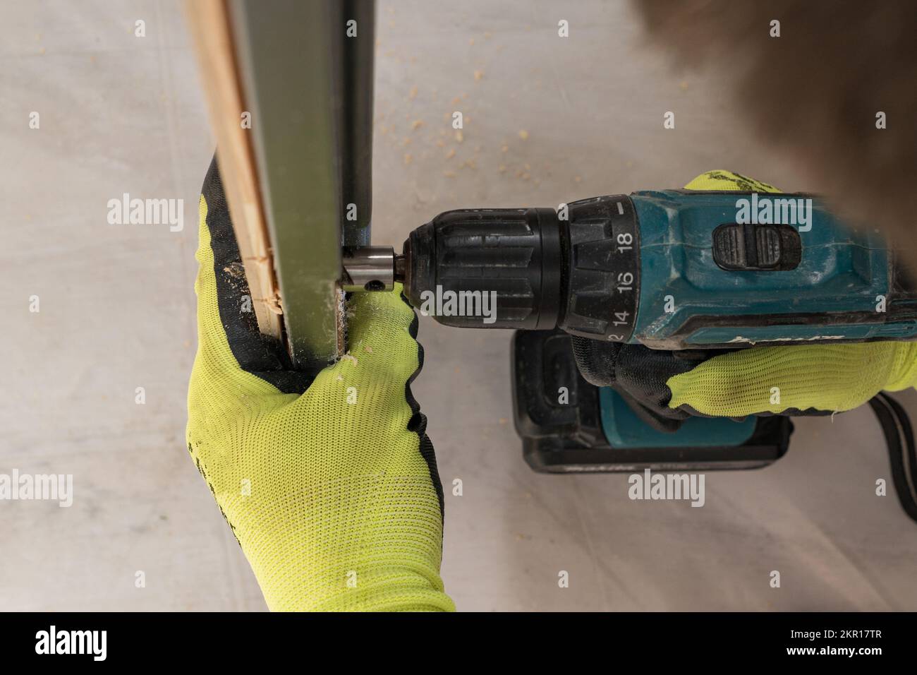 Drilling a hole in the door with a green screwdriver, closeup of the