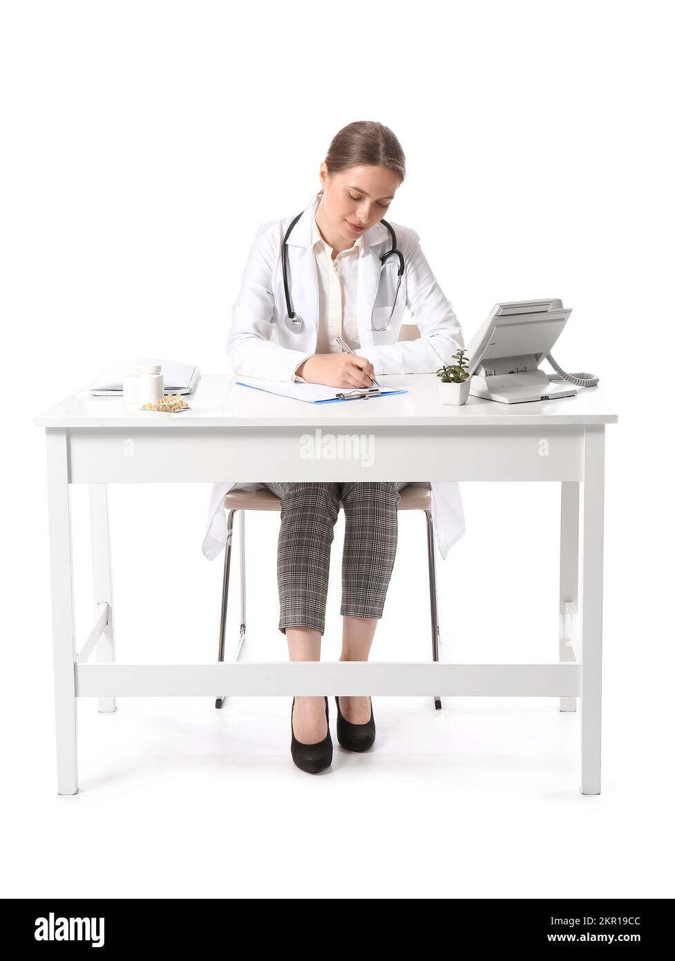Female doctor writing in clipboard at table on white background Stock ...