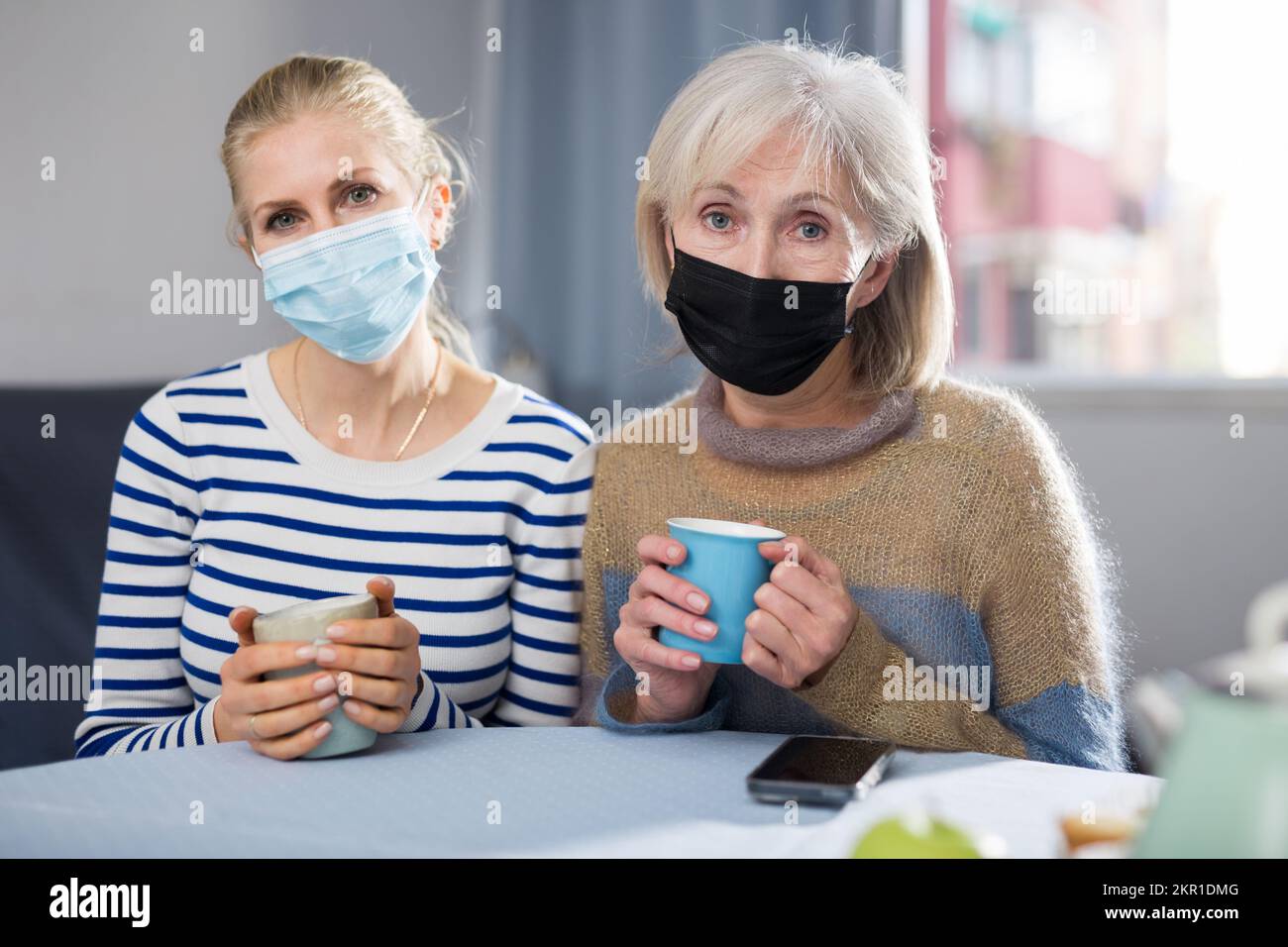 Two women in protective mask drink tea Stock Photo