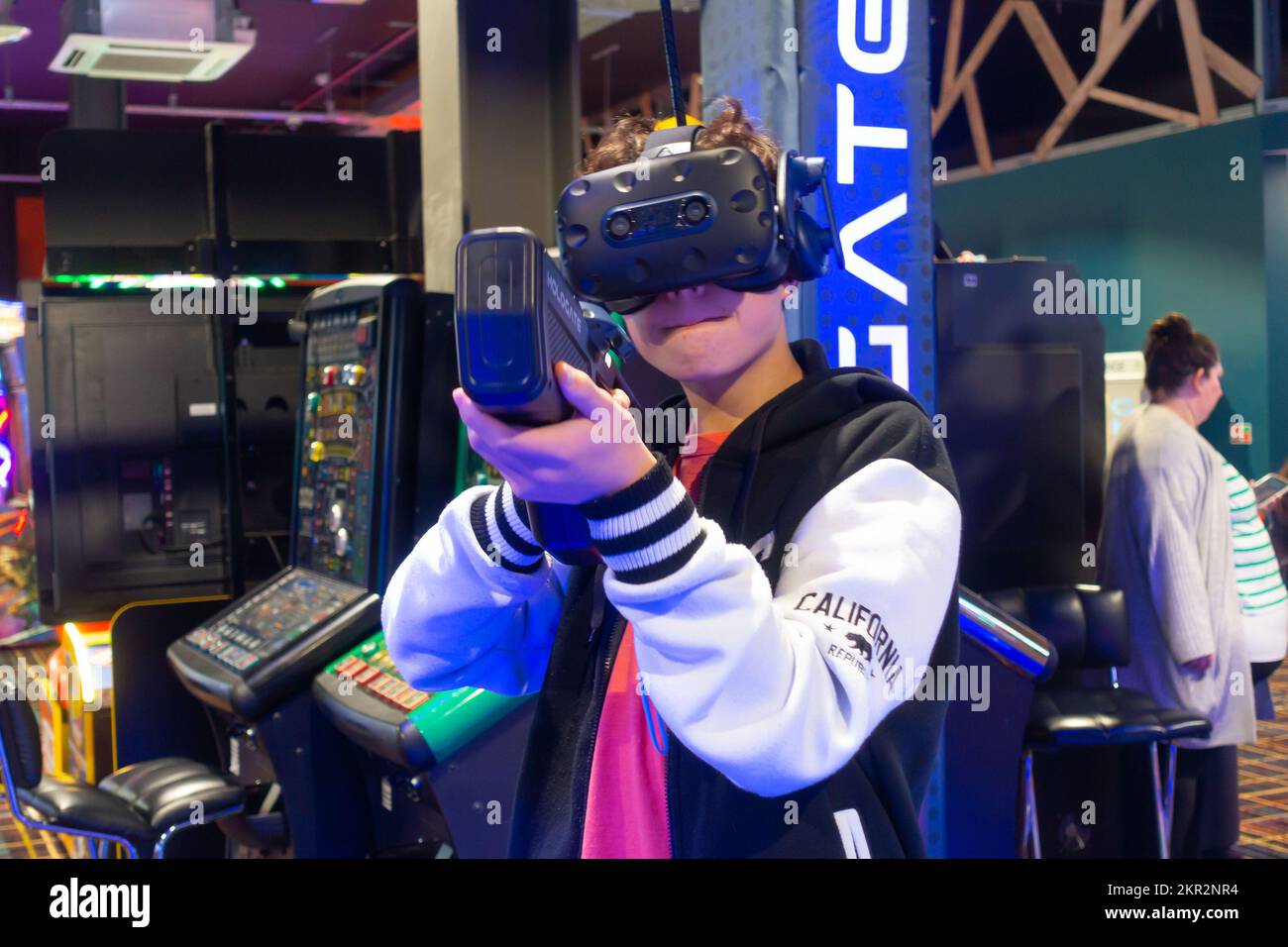 A boy playing a virtual reality video game in an arcade holding a