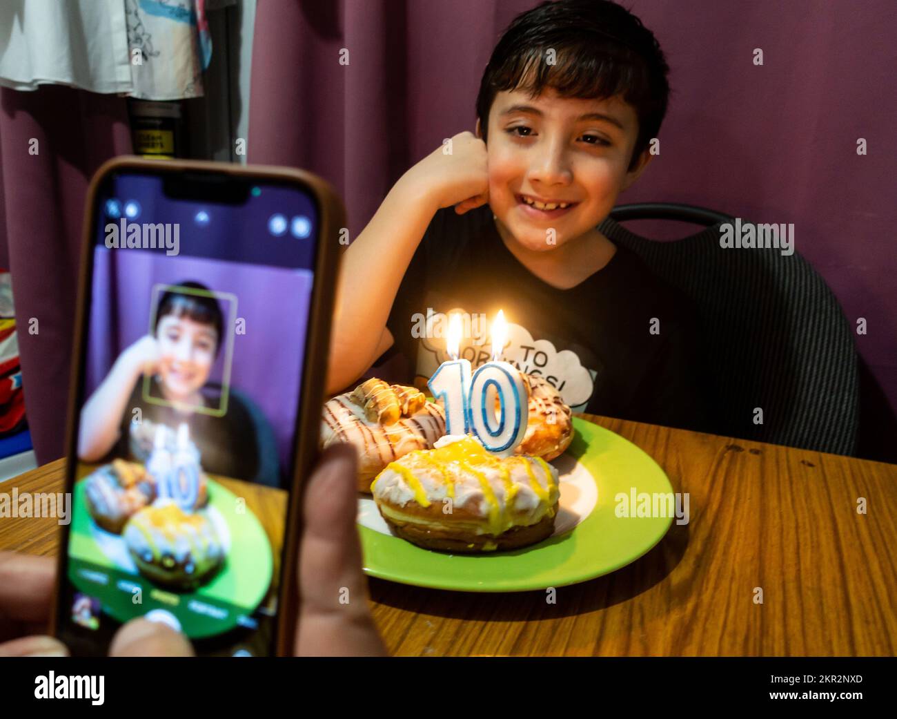 A Parent Takes A Photograph With A Mobile Phone Of A 10 Year Boy Posing a-parent-takes-a-photograph-with-a-mobile-phone-of-a-10-year-boy-posing