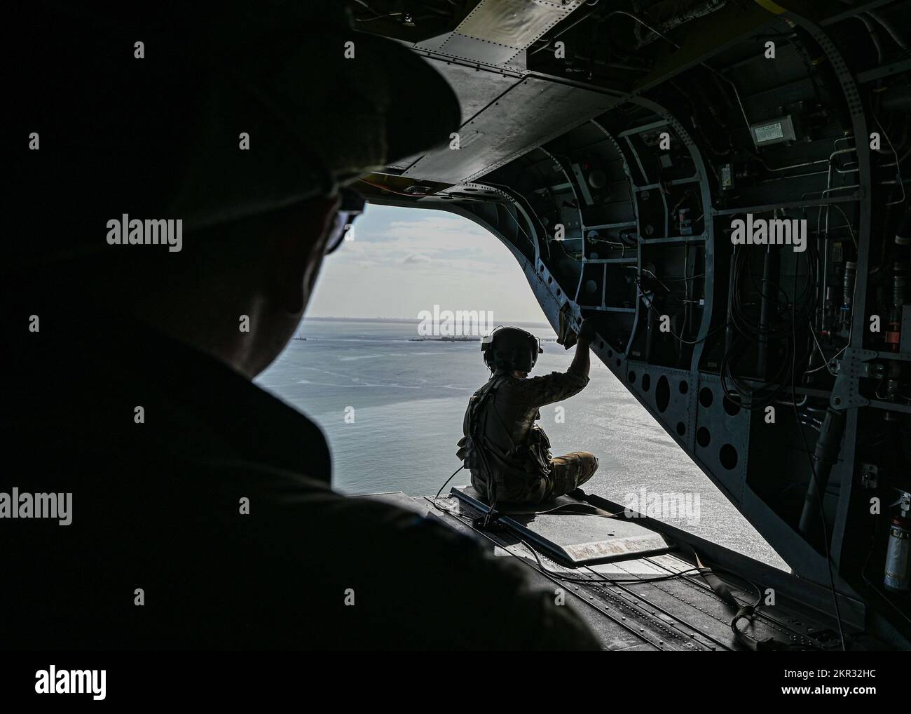 A U.S. Army soldier stands on the rear deck of a U.S. Army CH-47 Chinook as it flies over Virginia Beach, Virginia, while transporting U.S. Air Force Airmen assigned to the 355th Wing during Bushwhacker 22-07, Nov. 5, 2022. The Chinook and its aircrew made multiple trips a day delivering Airmen and equipment to the various simulated contingency locations during the exercise. (U.S. Air Force photo by Airman 1st Class Paige Weldon) Stock Photo