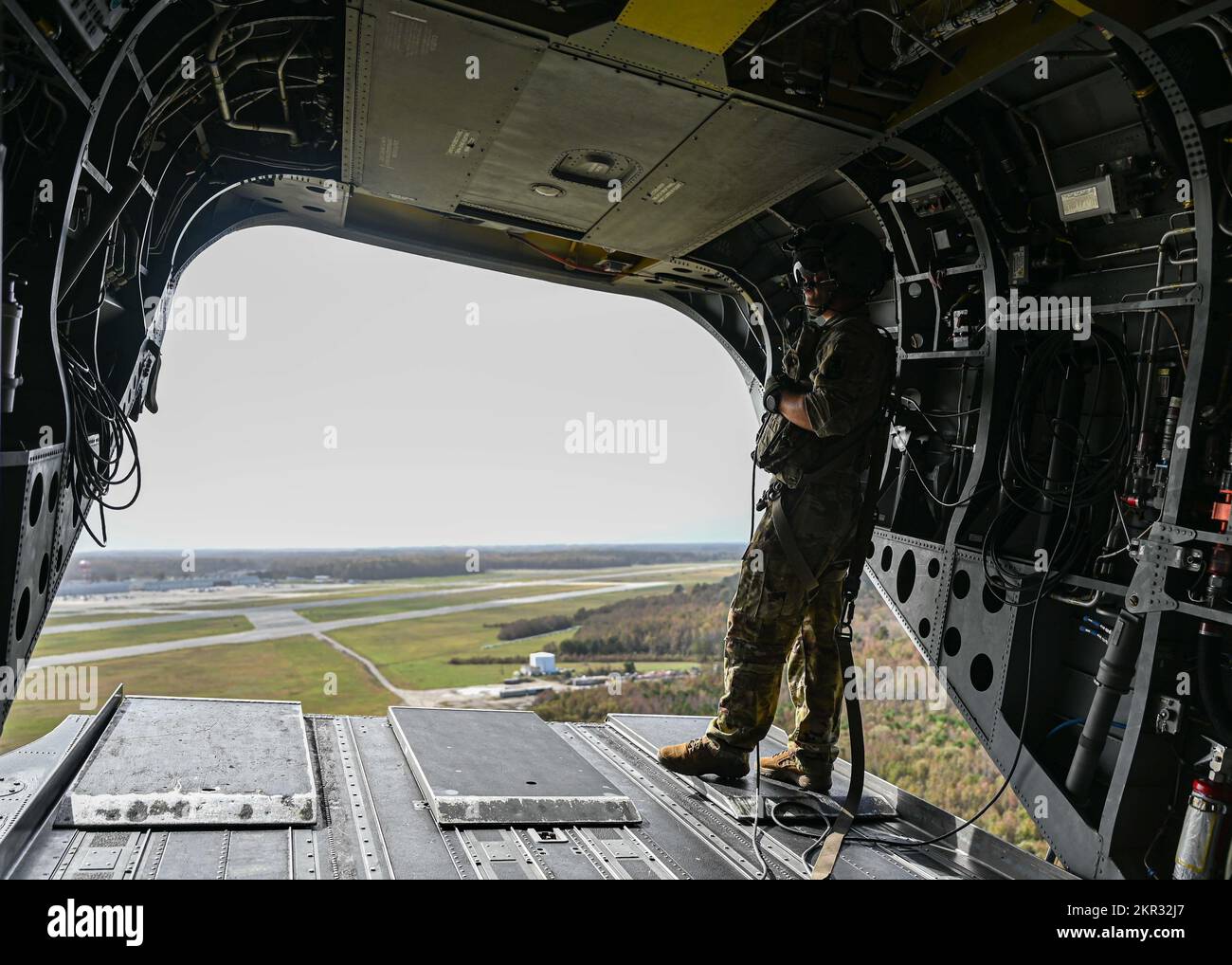 A U.S. Army soldier stands on the rear deck of a U.S. Army CH-47 Chinook as it flies over Naval Air Station, Virginia, while transporting U.S. Air Force Airmen assigned to the 355th Wing during Bushwhacker 22-07, Nov. 5, 2022. The Chinook and its aircrew made multiple trips a day delivering Airmen and equipment to the various simulated contingency locations during the exercise. (U.S. Air Force photo by Airman 1st Class Paige Weldon) Stock Photo