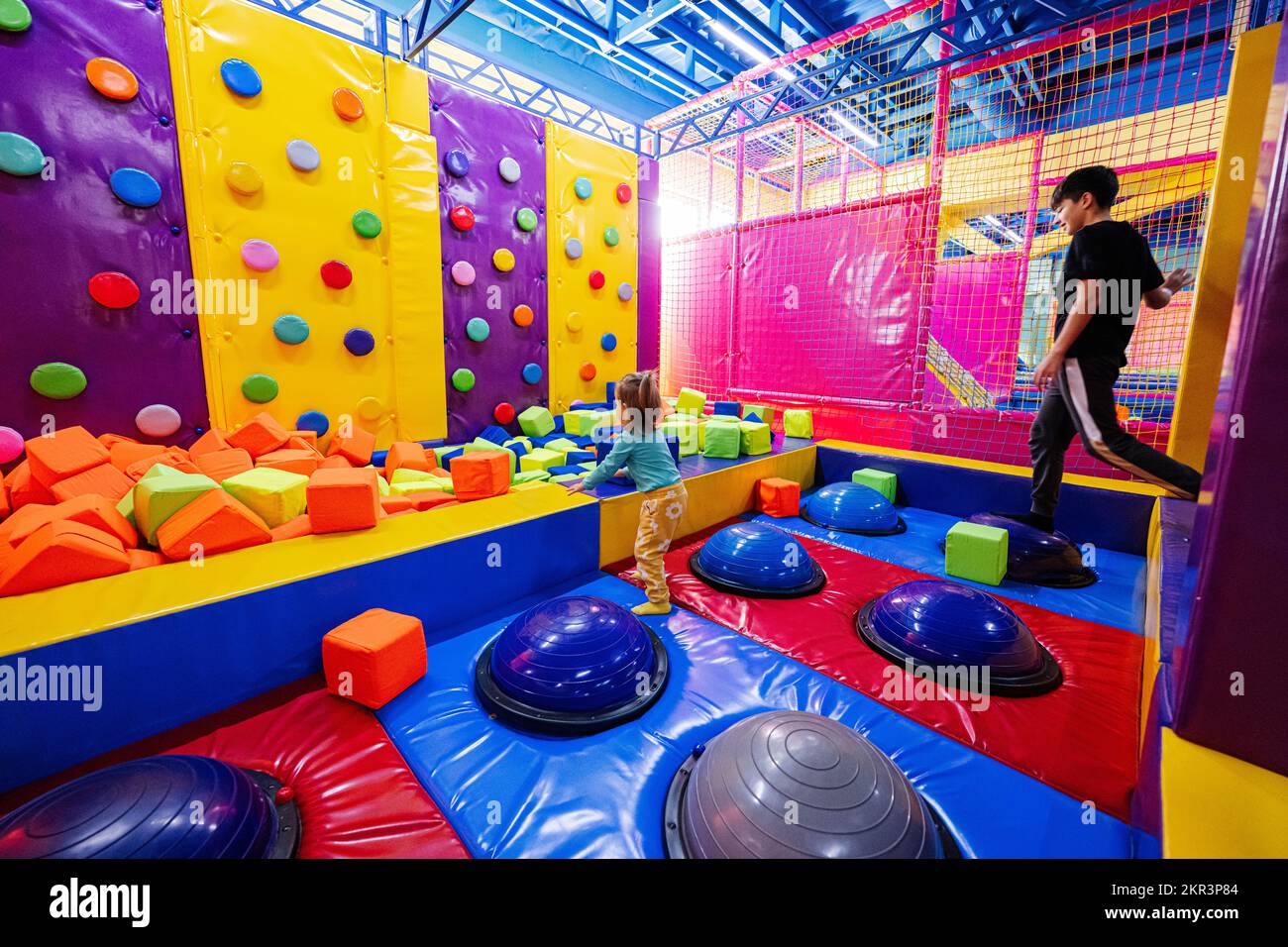 Brother with sister playing at indoor play center playground Stock
