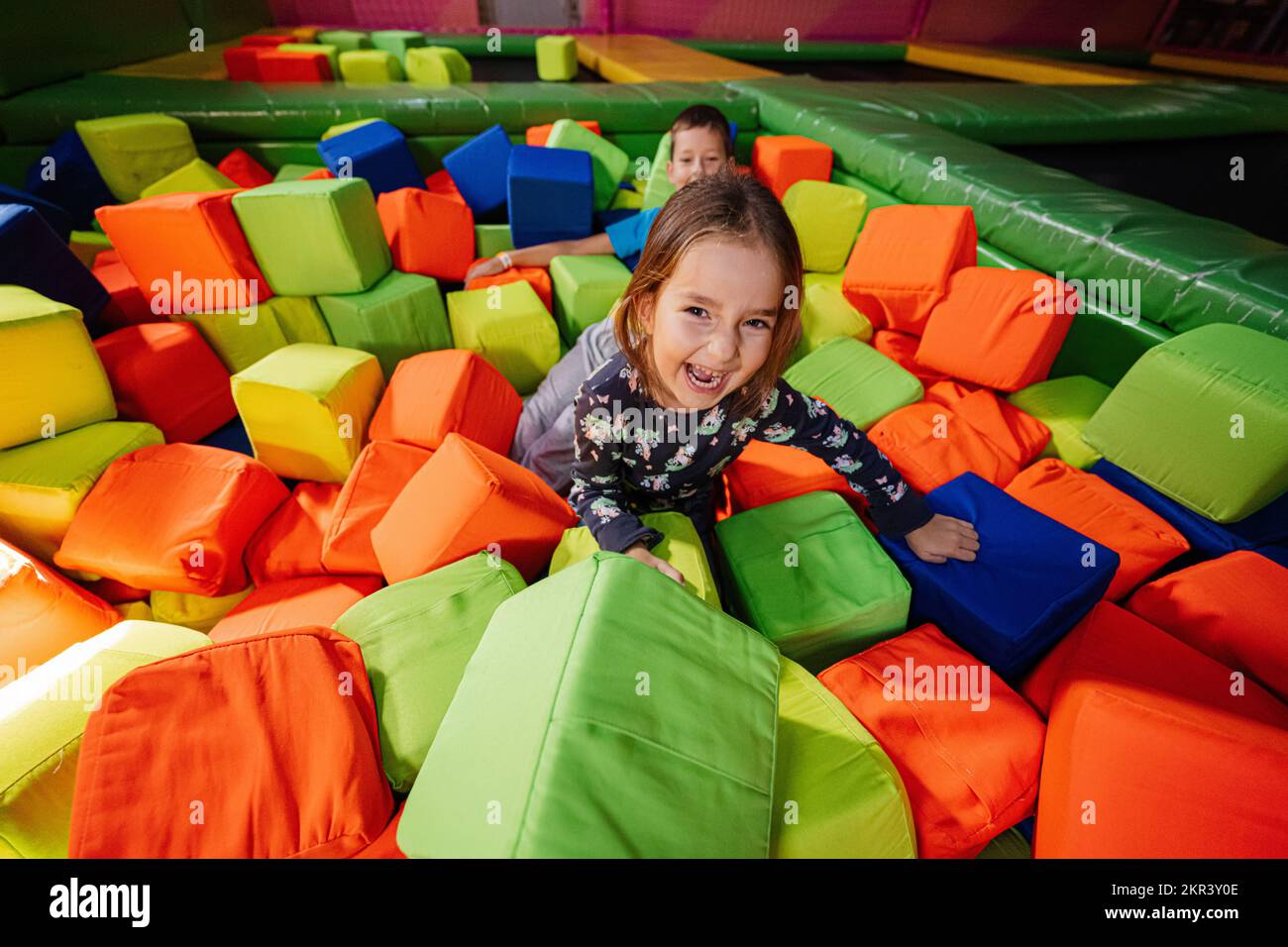 Brother with sister playing at indoor play center playground in color ...