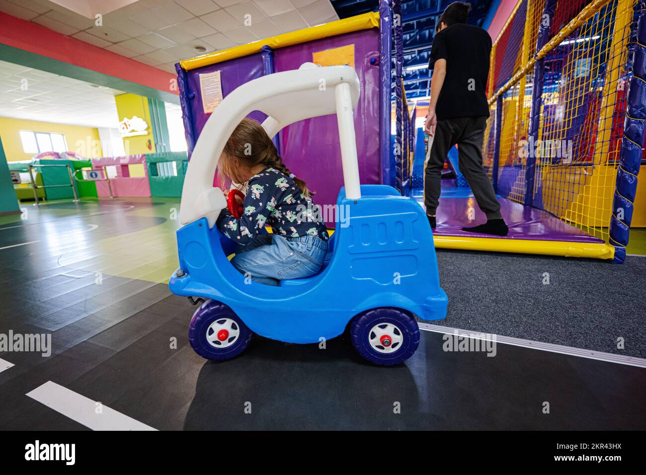 Kids playing at indoor play center playground , girl in toy car Stock