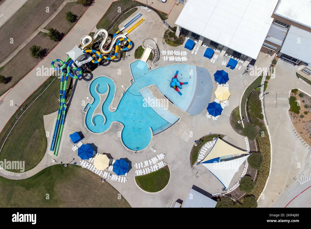 Aerial view from flying drone of aquapark, water park with various water slides, pool, sun loungers and green area. Stock Photo