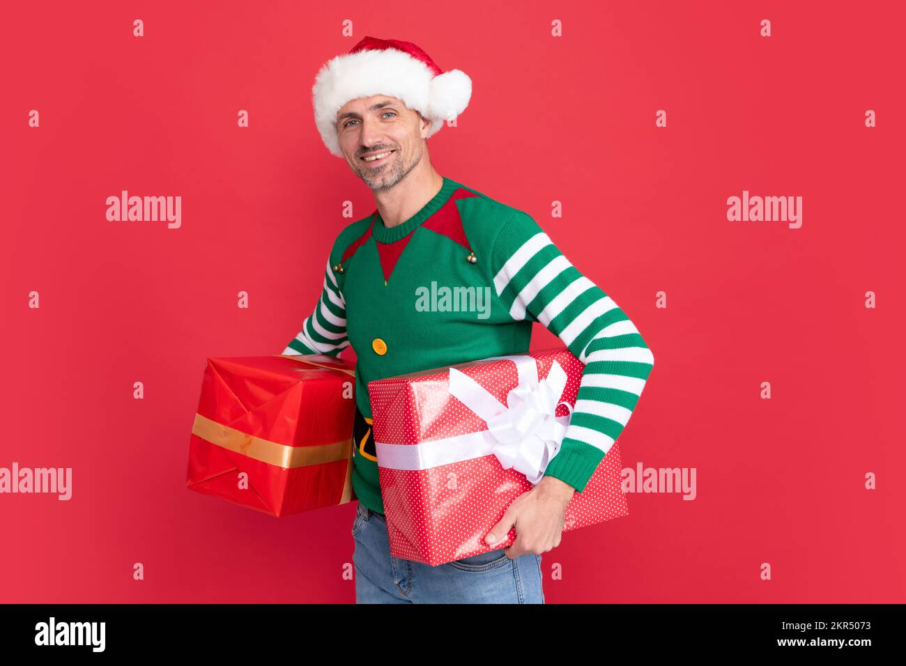 merry christmas gift. happy smiling man in elf costume and santa claus hat. xmas guy Stock Photo