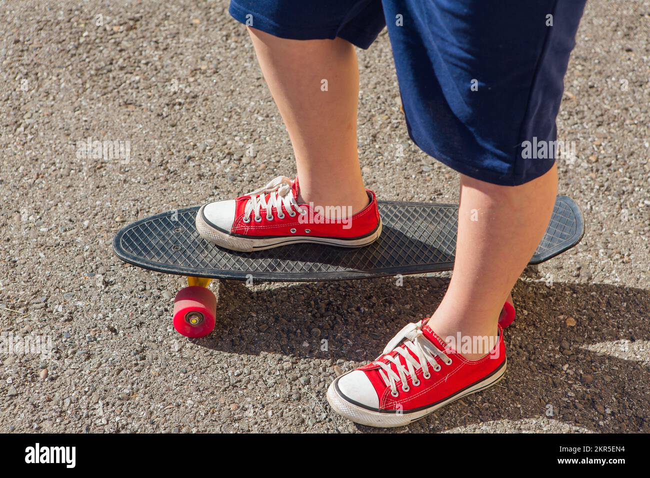Close up of feet of a boy in red sneakers rides on black penny skate board  with pink wheels. Urban scene, city life. Sport, fitness lifestyle Stock  Photo - Alamy