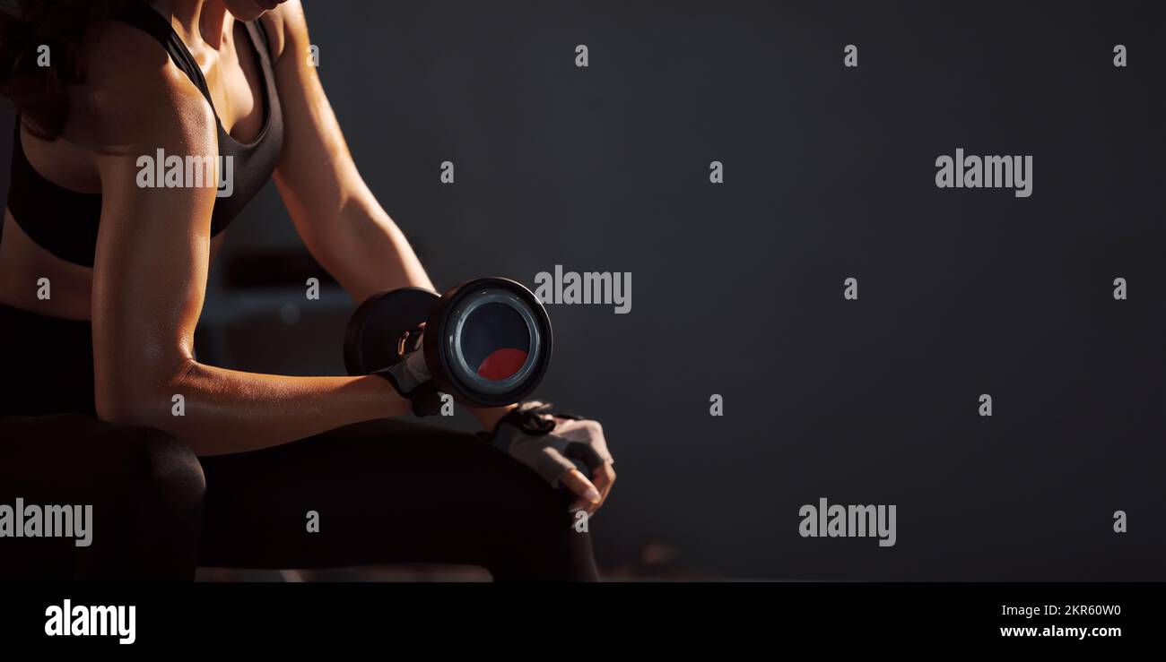 Sporty woman holding weight dumbbell doing fitness workout in the gym. Stock Photo