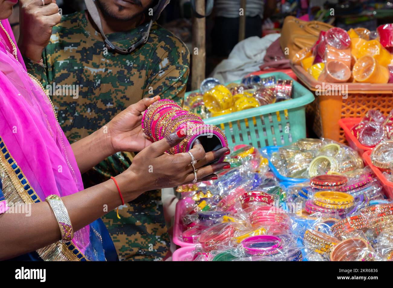 Rajasthani woman trying out colorful bangles. Bangles being sold at famous Sardar Market and Ghanta ghar Clock tower in Jodhpur, Rajasthan, India. Stock Photo