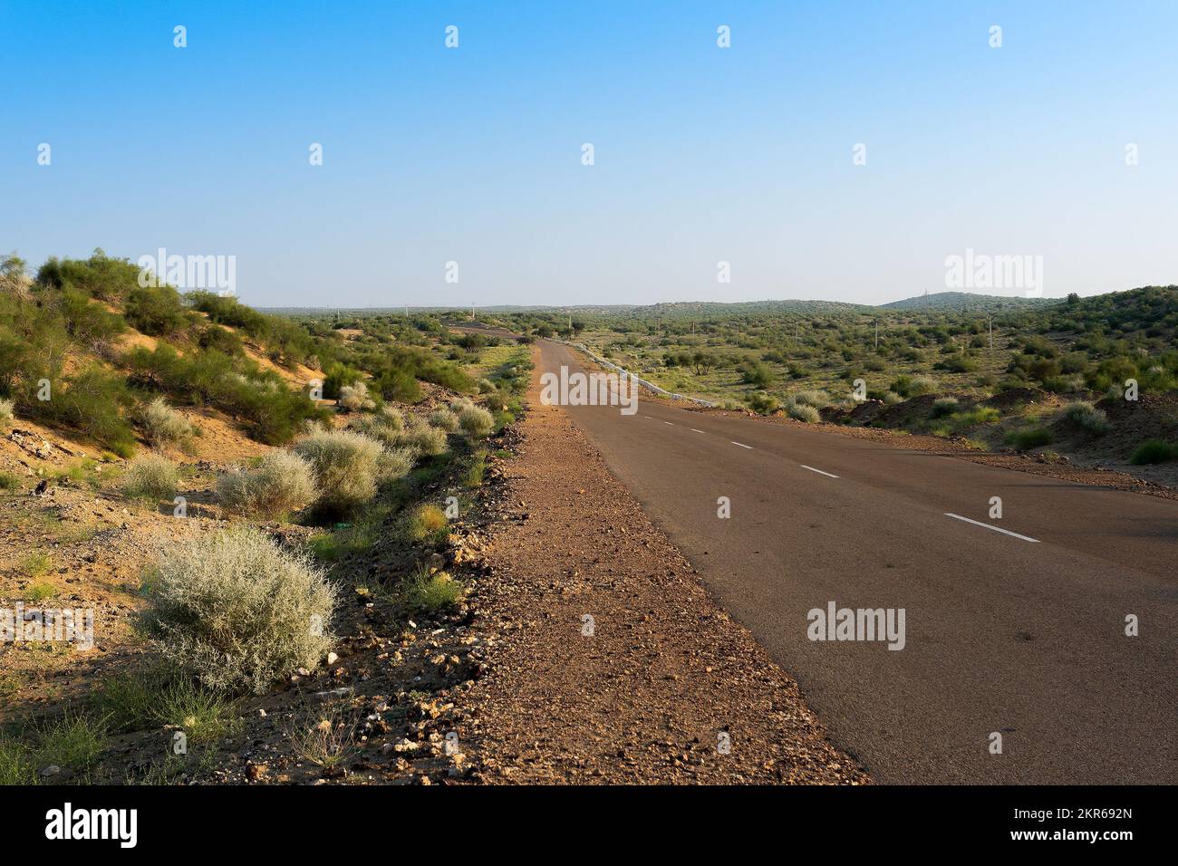 Morning in desert with empty high road or national high way passing through the desert. Distant horizon, Hot summer at Thar desert, Rajasthan, India. Stock Photo