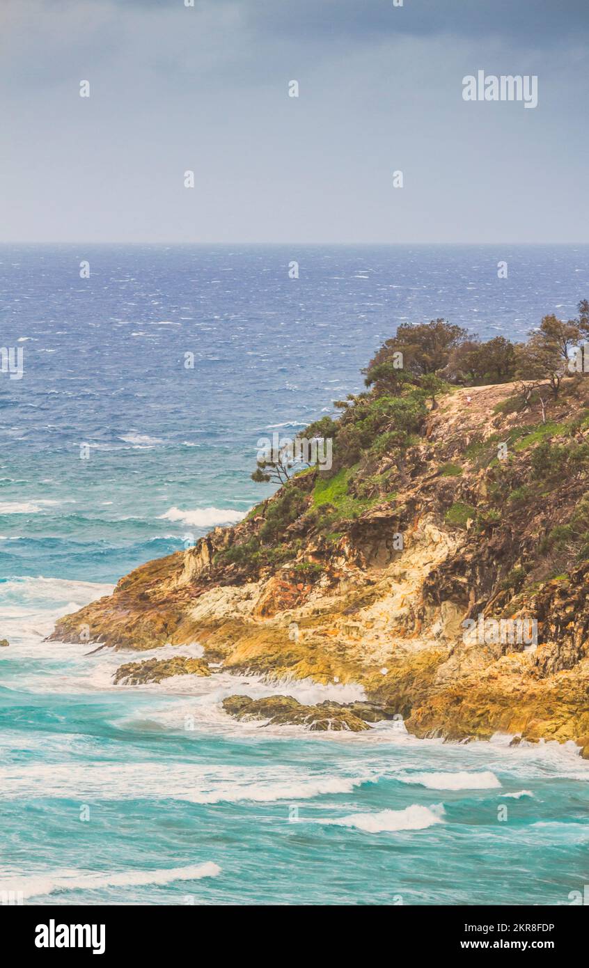 Colourful sea cliff in vertical format with wondrous flowing waters meeting rugged rocky cape. Photographed: Frenchman's Beach, Point Lookout, North S Stock Photo