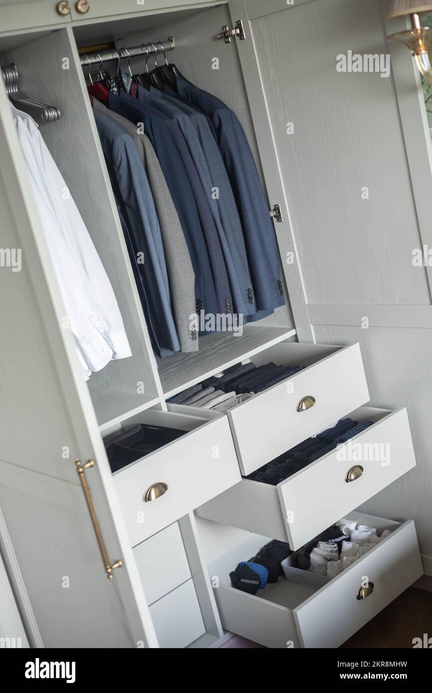 Minimalist male wardrobe neatly folded and hanging clothes dresser