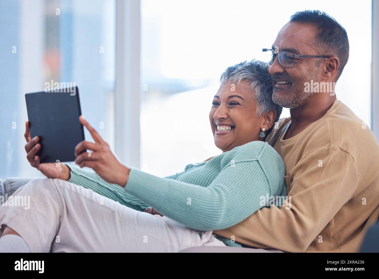 Movie, communication and senior couple with a tablet, streaming film and show on the living room sofa of their house. Website, social media and Stock Photo