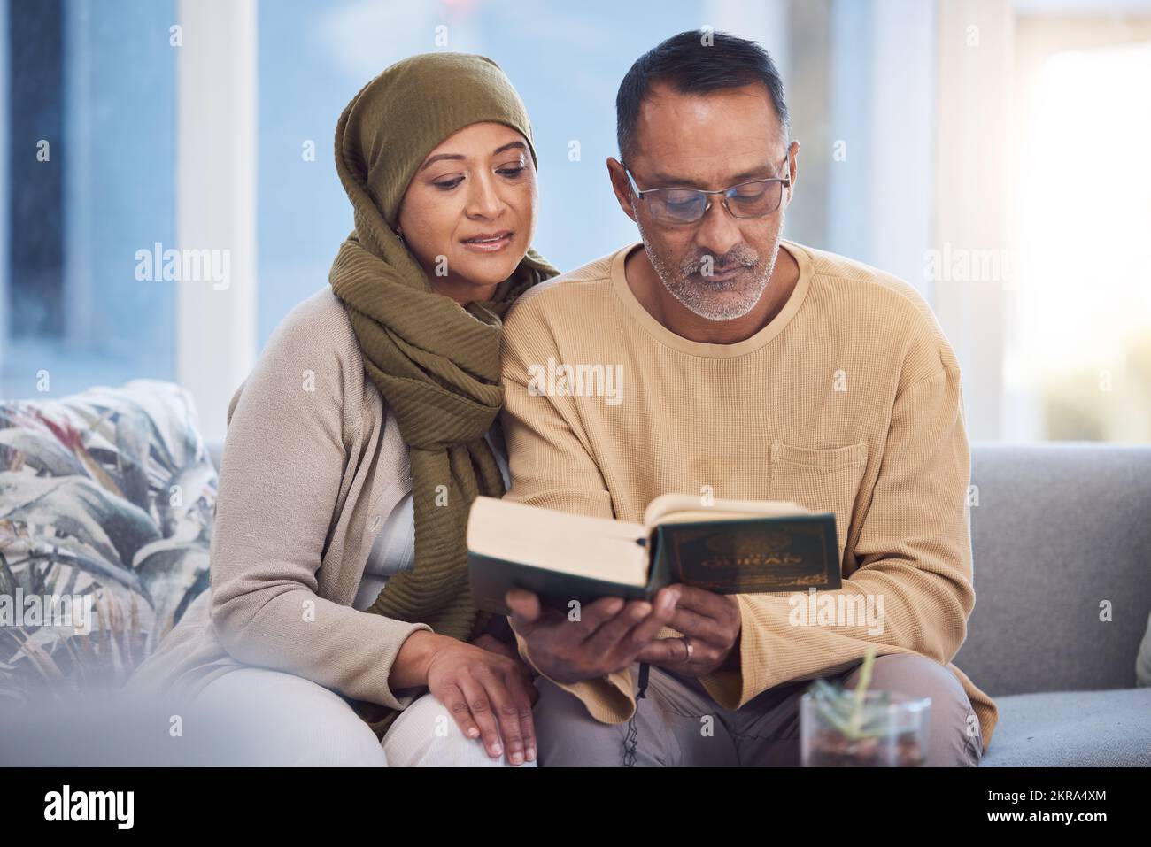 Reading, book and eid mubarak with a muslim couple in the living room of their home together with the quran. God, Islam and ramadan with a man and Stock Photo