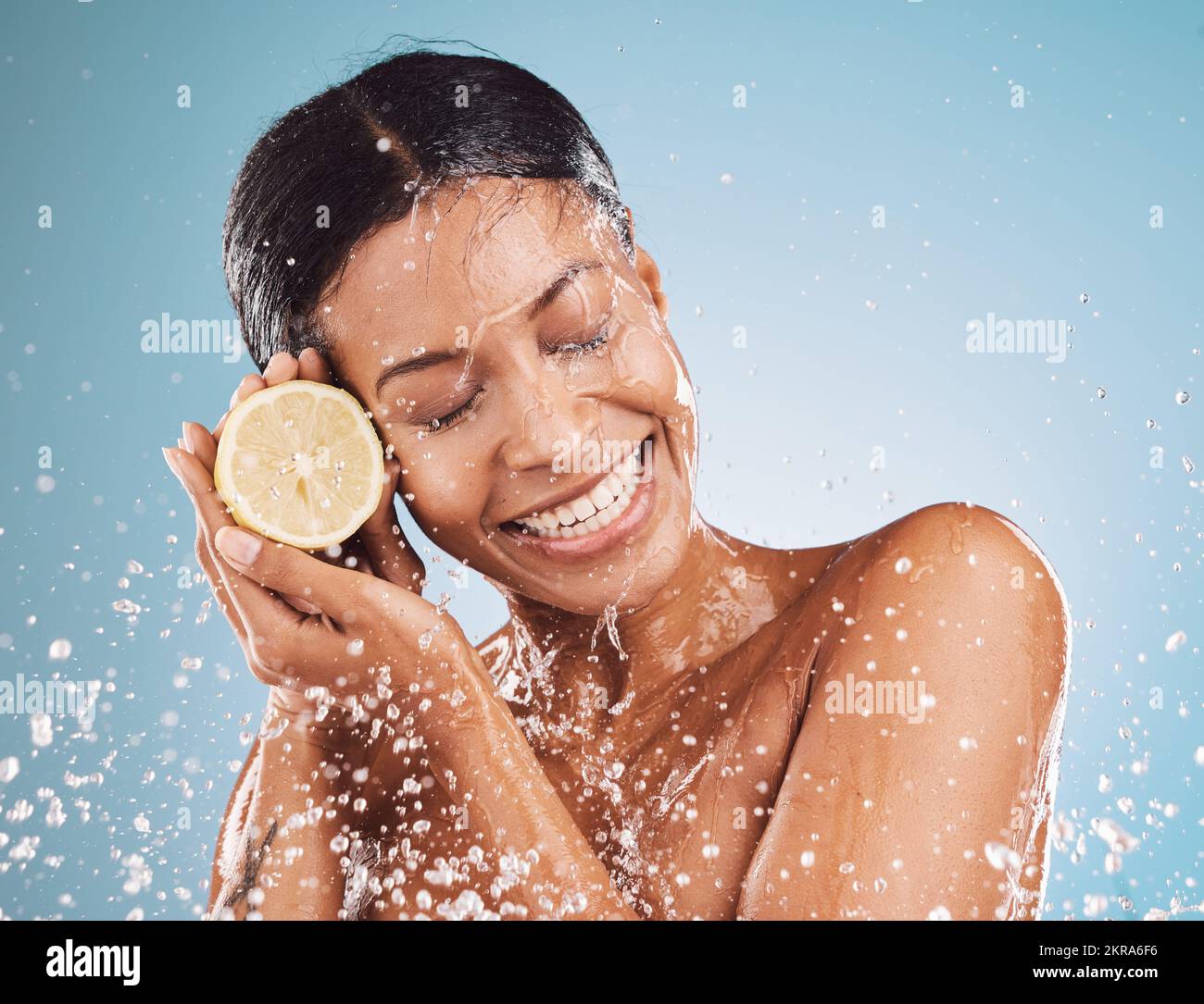 Face, water splash and skincare of woman with lemon in studio isolated