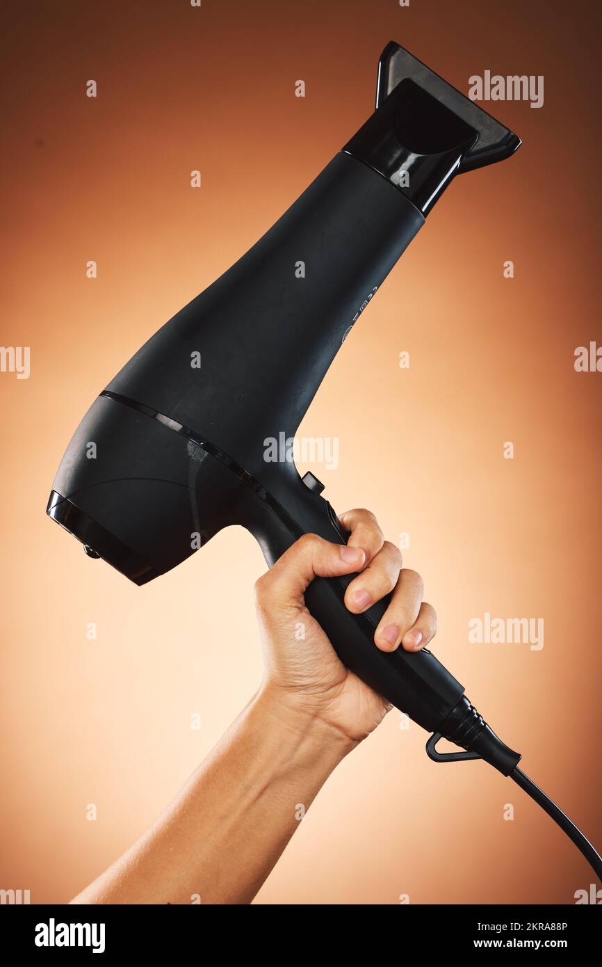 Hair, hand with hair dryer and hair care with beauty and cosmetic advertising against orange studio background. Salon, hairdressing and hairstyle tool Stock Photo