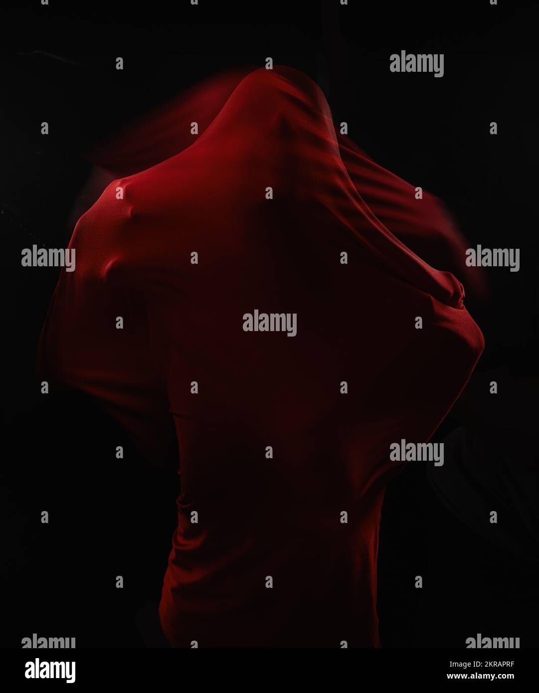 Engulfed by fear. A human figure trapped in red fabric and struggling to break free while