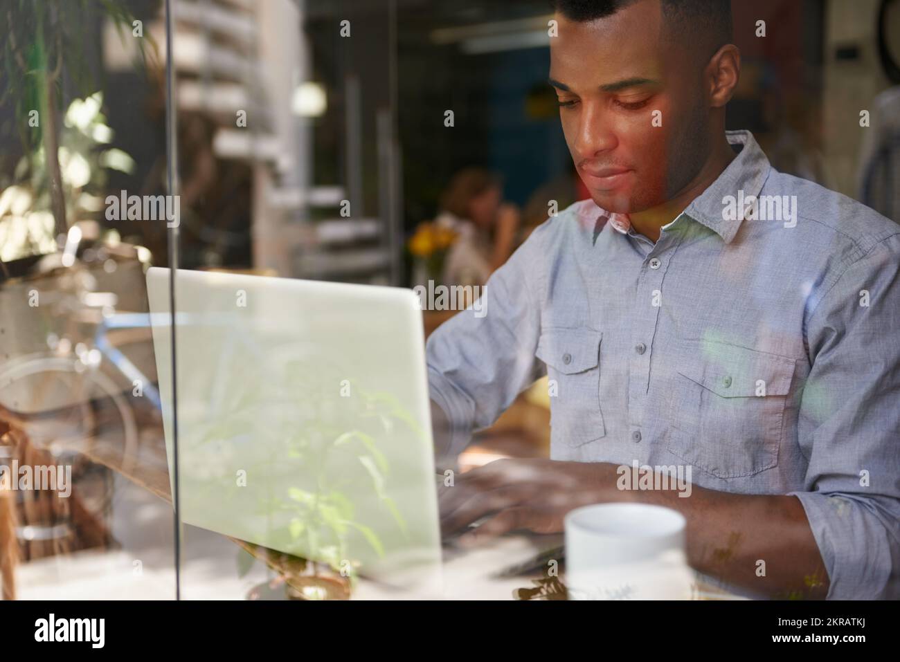 Gotta get this work done. a young ethnic man using his laptop in a coffee shop. Stock Photo