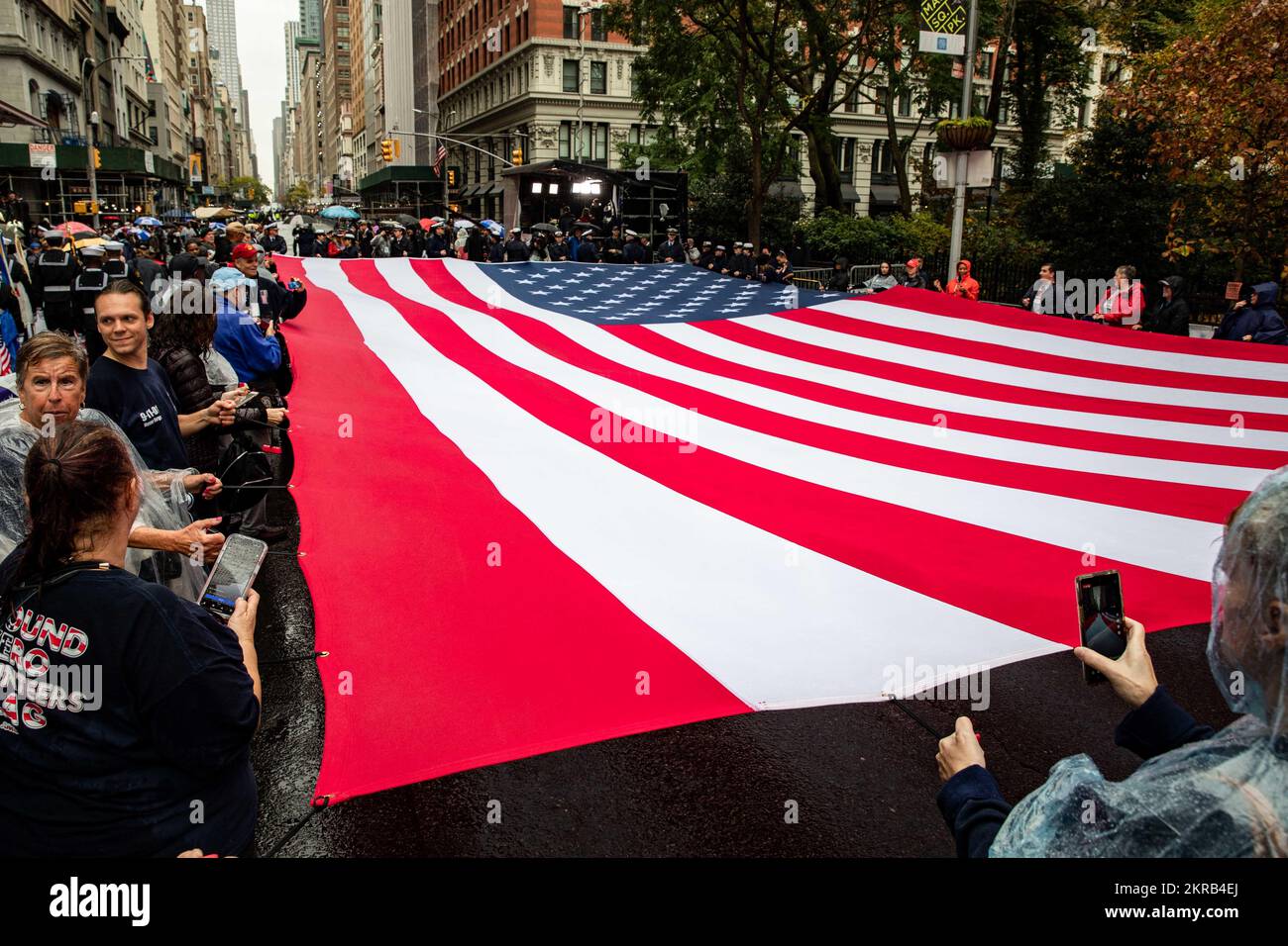A jumbo-sized American flag is unfurled at the New York City Veterans Day Parade, Nov. 11, 2022. Sailors assigned to the San Antonio-class amphibious transport dock ship USS Arlington (LPD 24) and II Marine Expeditionary Force (MEF) Marines are participating in events in and around New York City during the week-long Veterans Day New York celebration to honor the service and sacrifice of the nation’s veterans. Stock Photo