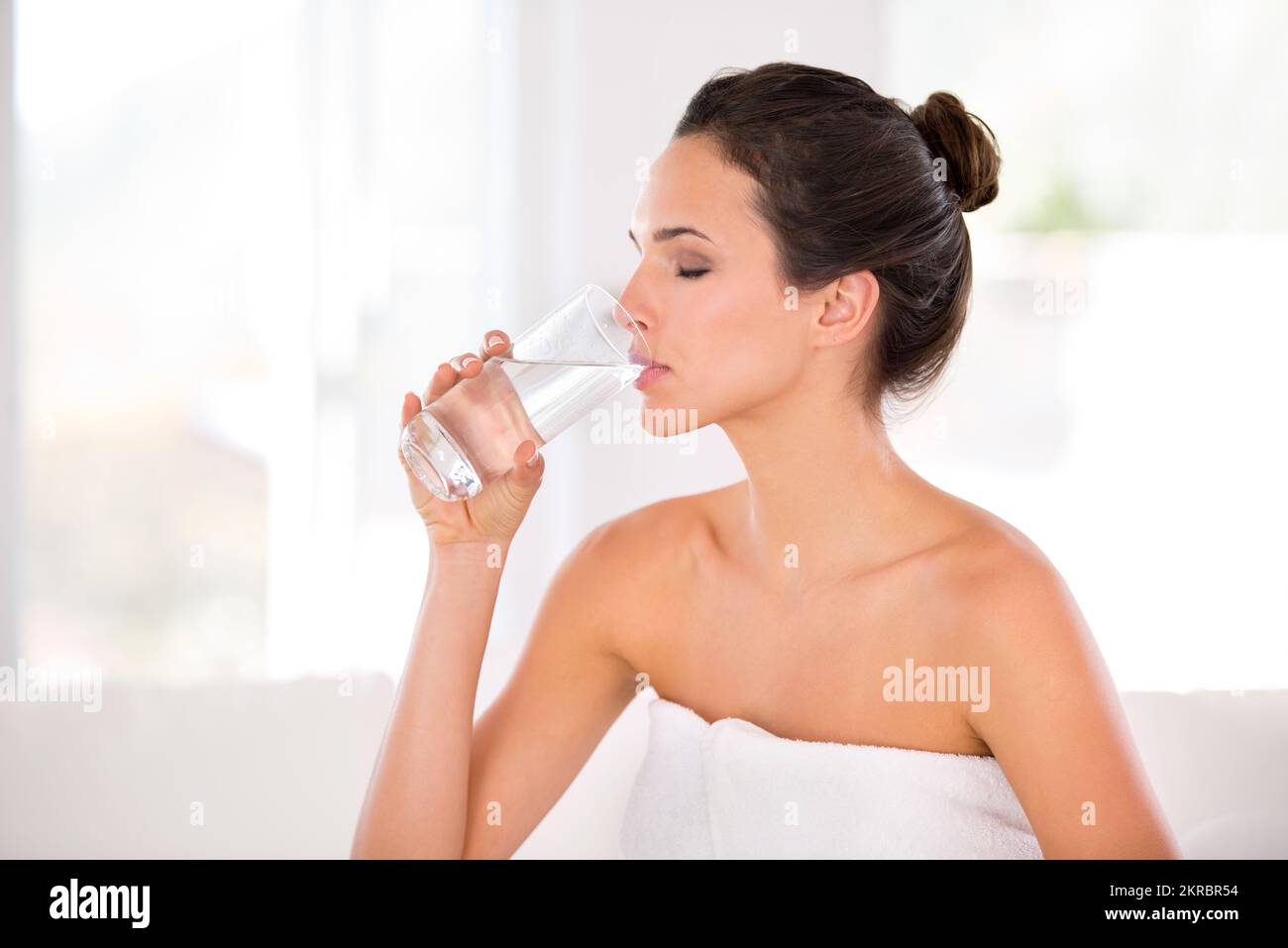 Rejuvenating her skin. Side view of a beautiful woman drinking a glass of water. Stock Photo
