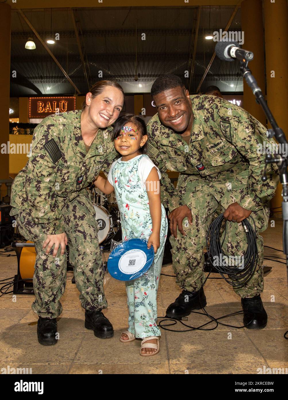 Musician 2nd Class Alyssa John, from Hettinger, North Dakota, left, and Musician 1st Class Brandon Britt, from Bowling Green, Kentucky, both assigned to U.S. Fleet Forces Band, pose for a photo with a child after a performance at La Castellana Shopping Mall in Cartagena, Colombia during Continuing Promise 2022, Nov. 13, 2022. CP22 is a humanitarian assistance and goodwill mission conducting direct medical care, expeditionary veterinary care, and subject matter expert exchanges with five partner nations in the Caribbean, Central and South America. Stock Photo