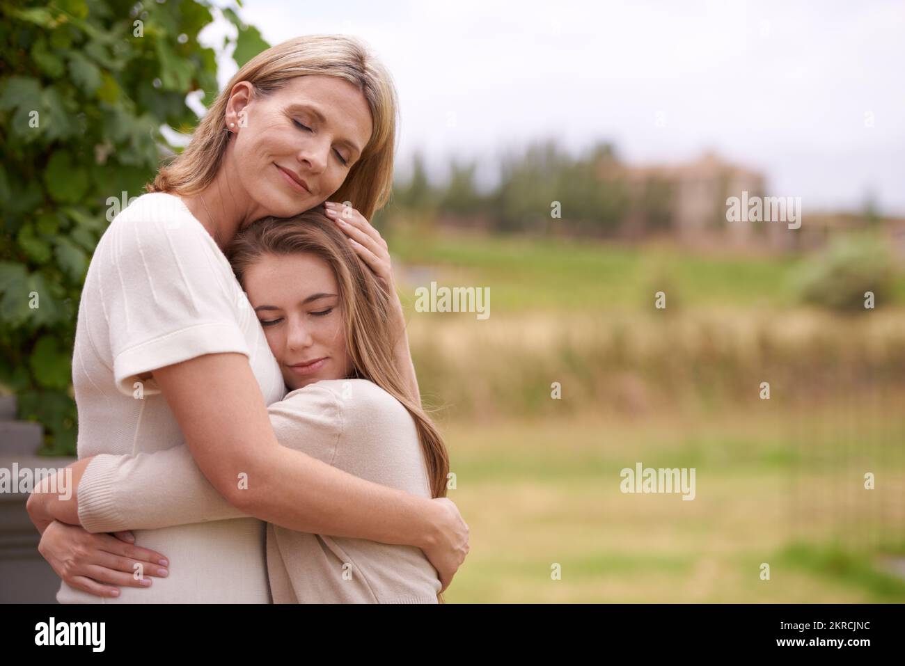 Their love for each other is so tangible. A mother embracing her daughter in an outdoor setting. Stock Photo