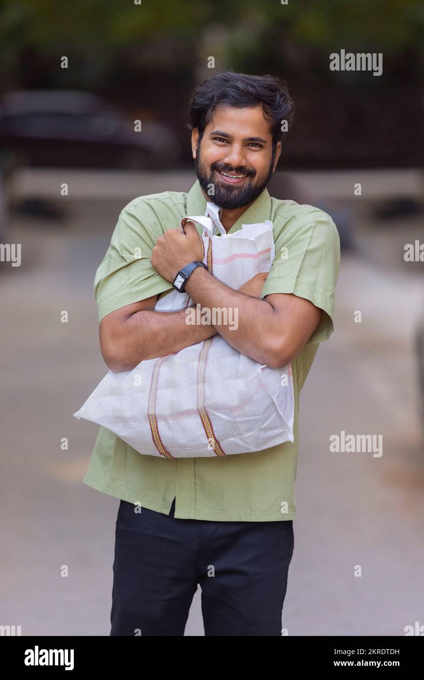 Happy young man standing on street with clutching bag to his chest Stock Photo