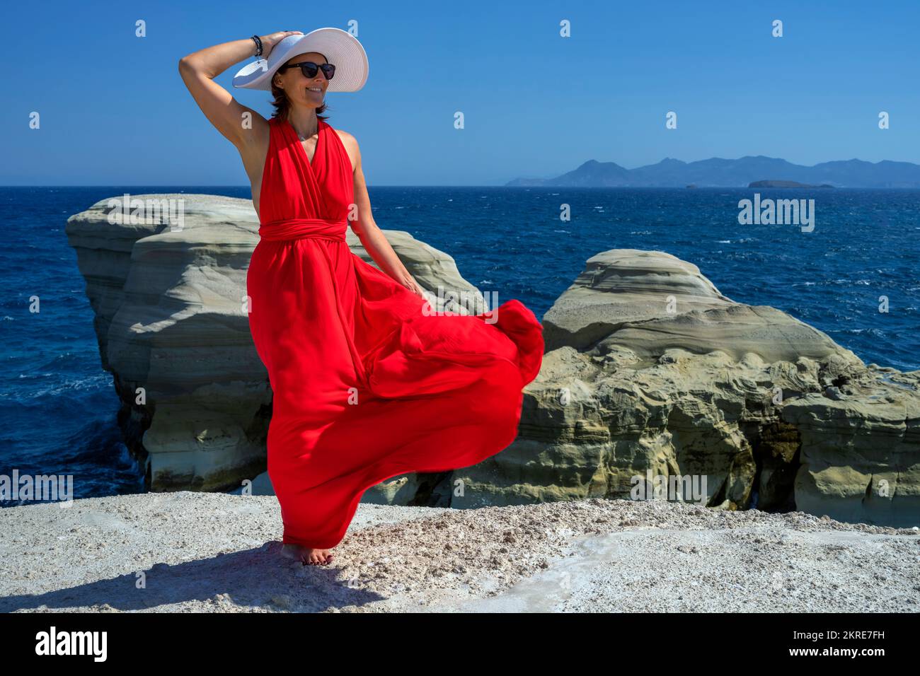 red dressed woman in the wind, Santorini Stock Photo