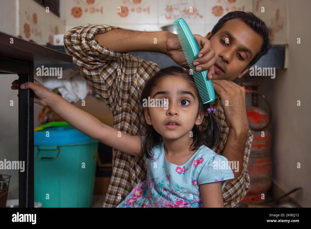 Father combing his daughter's hair in the kitchen Stock Photo