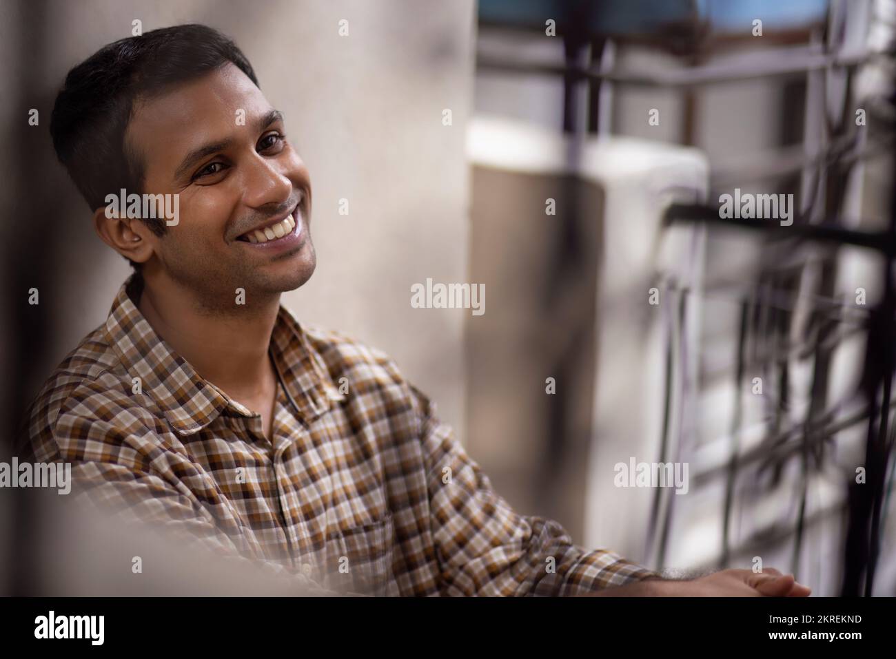 Portrait of smiling young man leaning against wall Stock Photo - Alamy