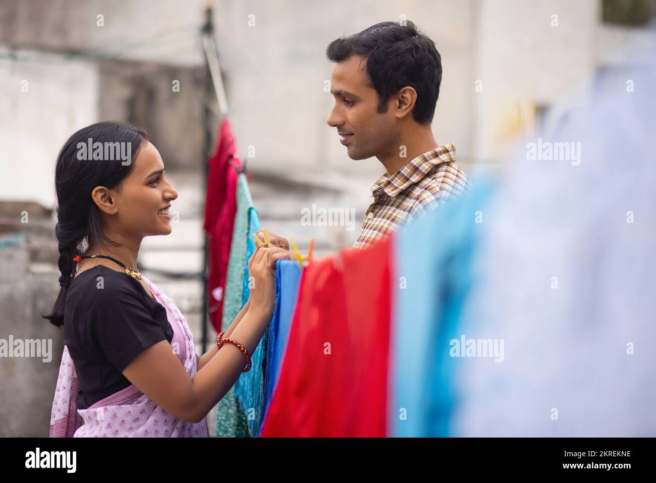 Couple hanging out wet clothes on washing line in the backyard Stock Photo