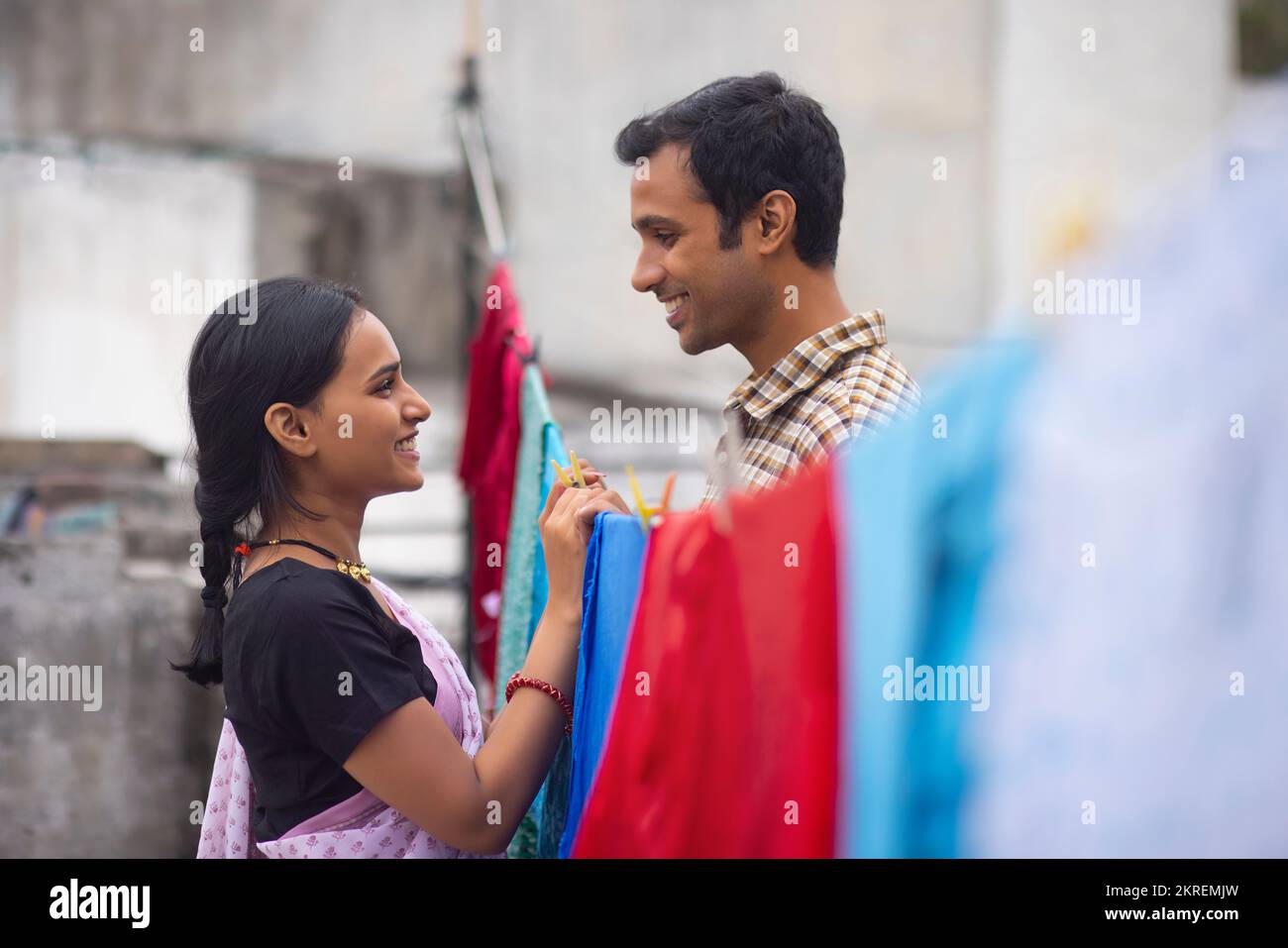 Couple hanging out wet clothes on washing line in the backyard Stock Photo