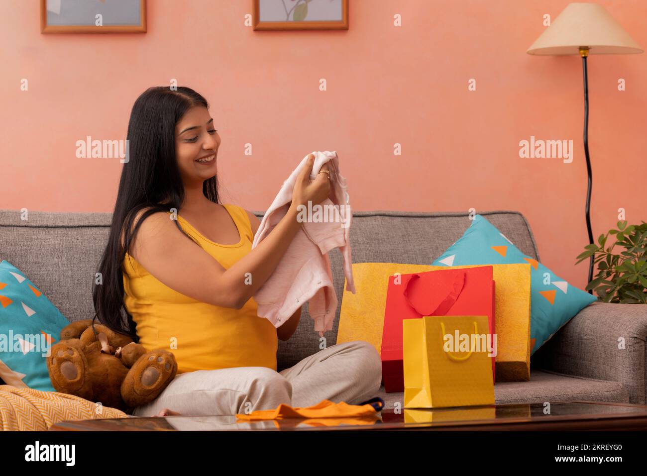 Pregnant woman watching the first clothes for her still unborn baby Stock Photo