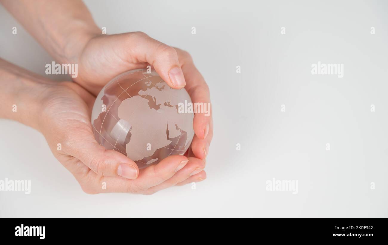 Crystal globe in female hands on a white background.  Stock Photo