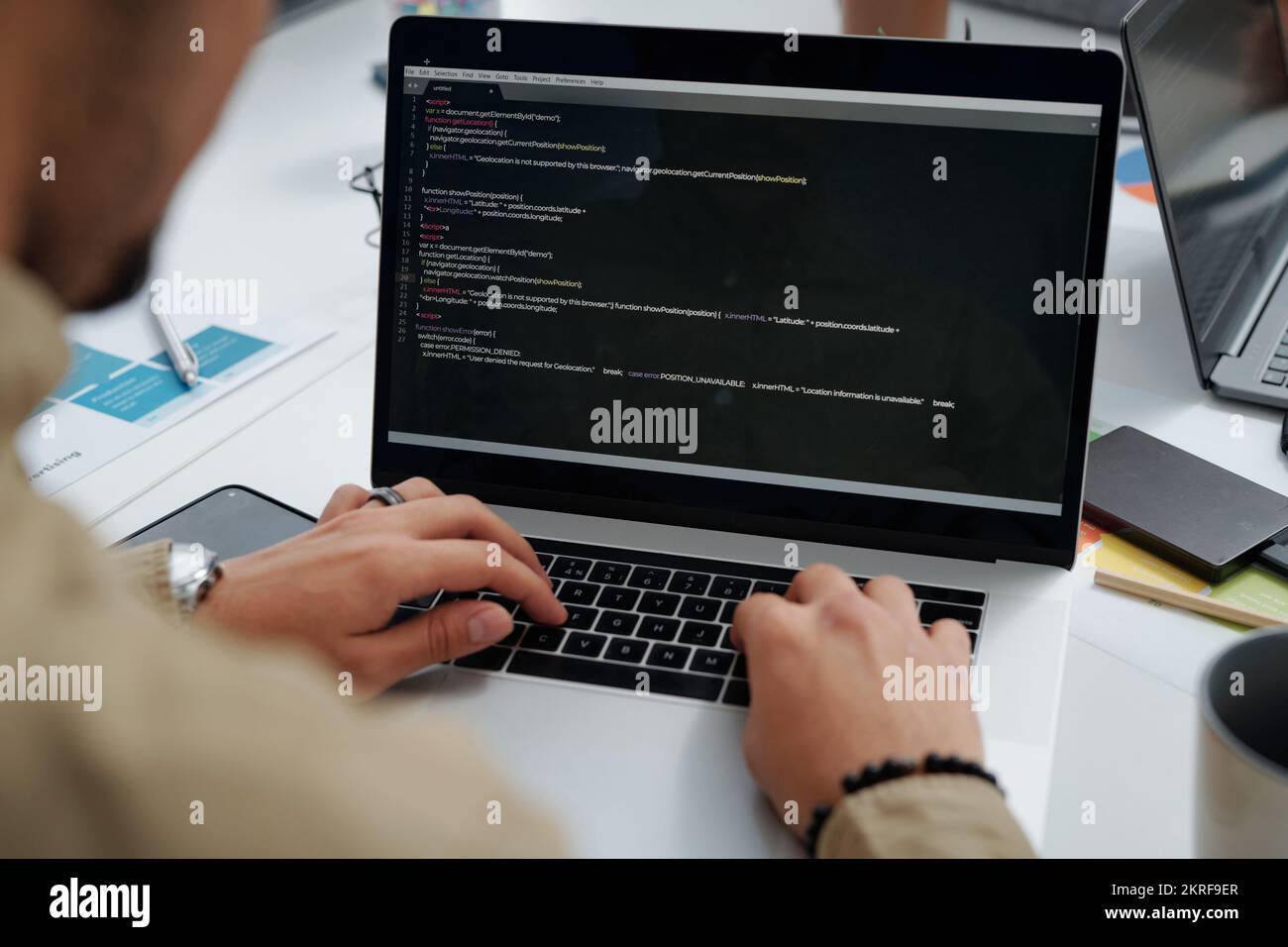 Close-up of young developer writing codes on computer while working at table at IT office Stock Photo