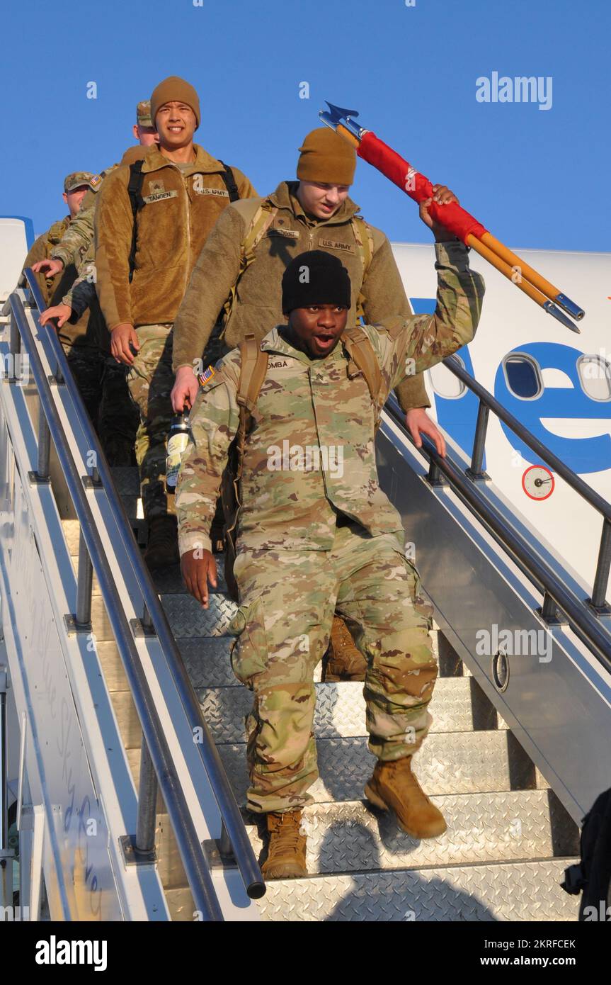 Sgt. Yajua Kiromba, 957th Engineer Company (Multi-role Bridge), expresses his joy by waving the unit’s guidon on a chartered flight at the Bismarck Municipal Airport on Nov. 15, 2022, Bismarck, North Dakota. Kiromba was among 70 Soldiers aboard which comprised the main body of the approximately 120 Soldiers who recently completed a year-long mission in support of the Customs and Border Protection’s (CBP) along the southwest border. Stock Photo