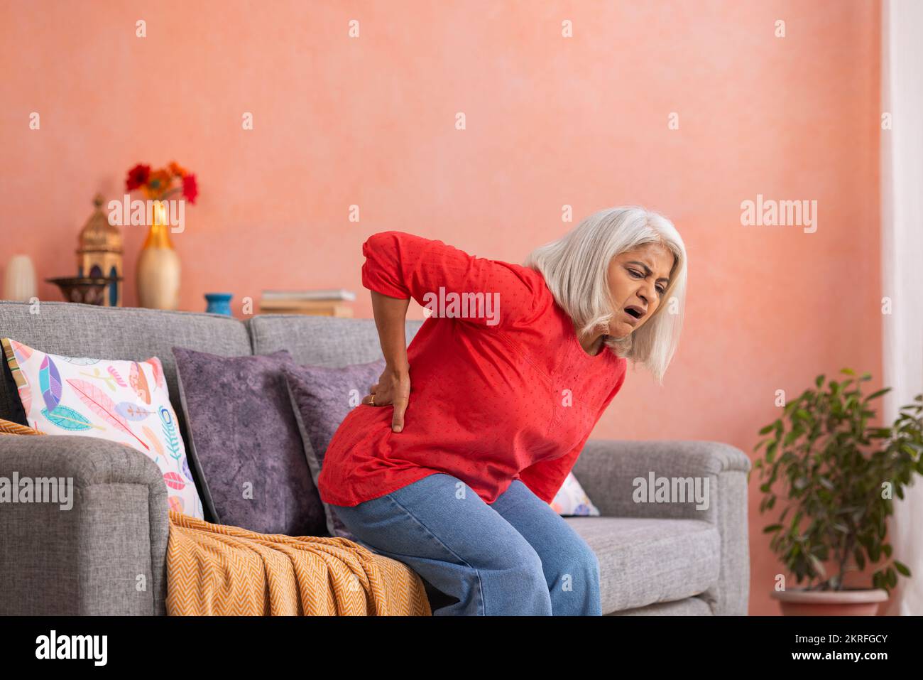 Old woman suffering from back pain at home Stock Photo