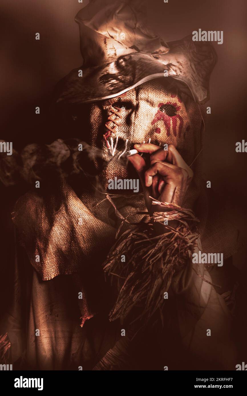 Dark horror portrait of a sinister scarecrow smoking cigarette in a dark night field. The draw of nightmares Stock Photo