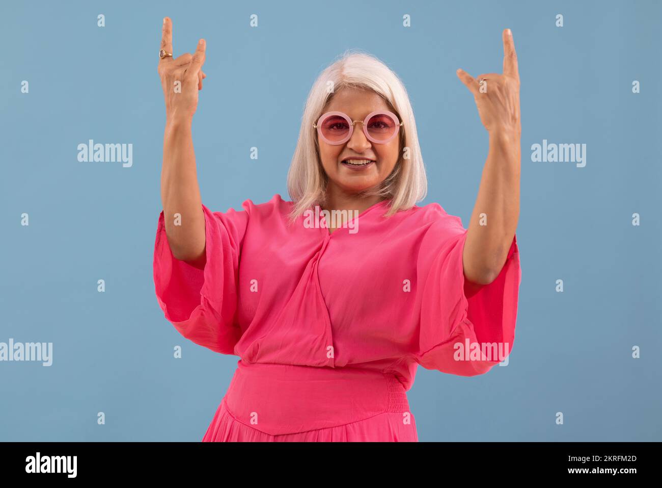 Portrait of an old lady cheering against blue background Stock Photo