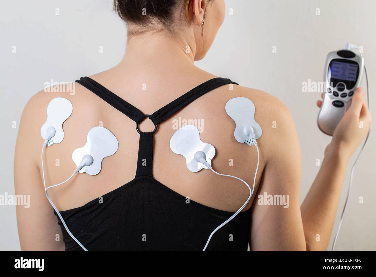Acupuncture electronic massager on the back of a girl to relax muscles
