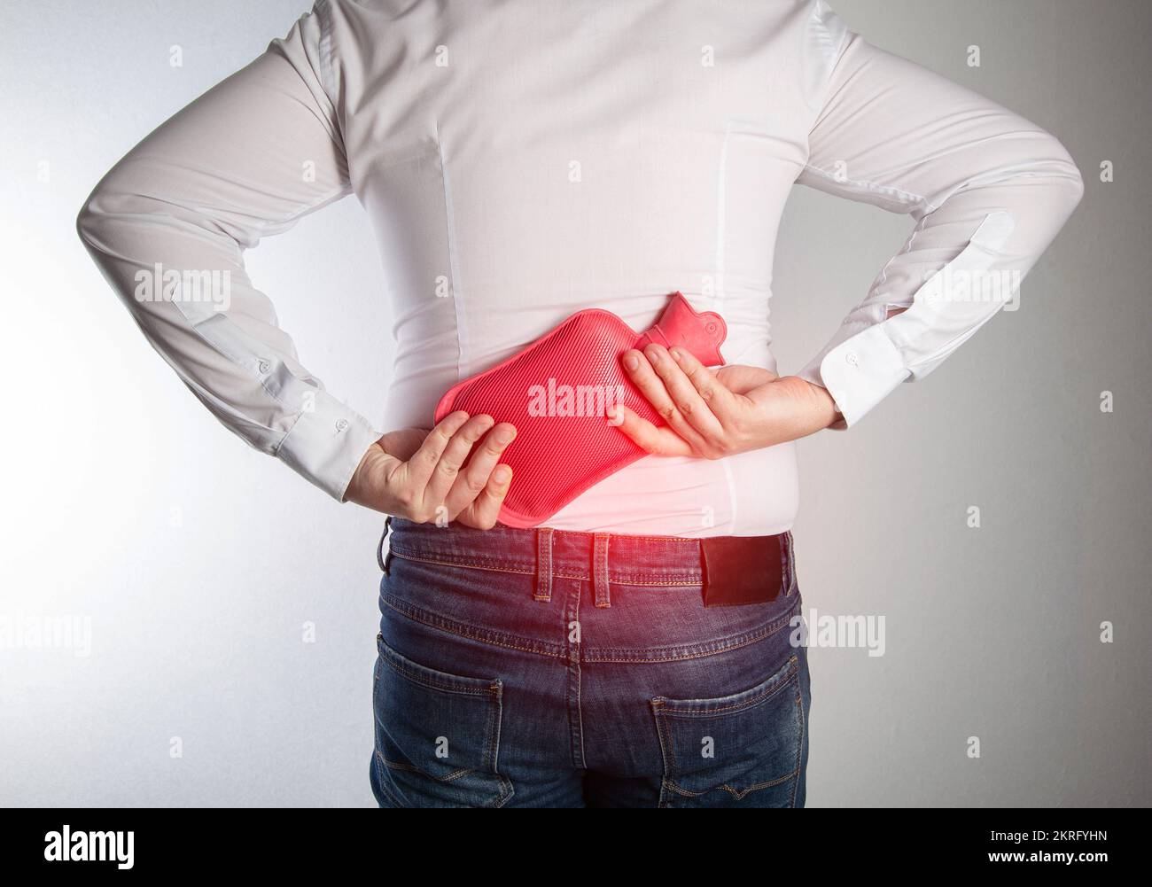 A man holds a medical heating pad with hot water in the lumbar spine