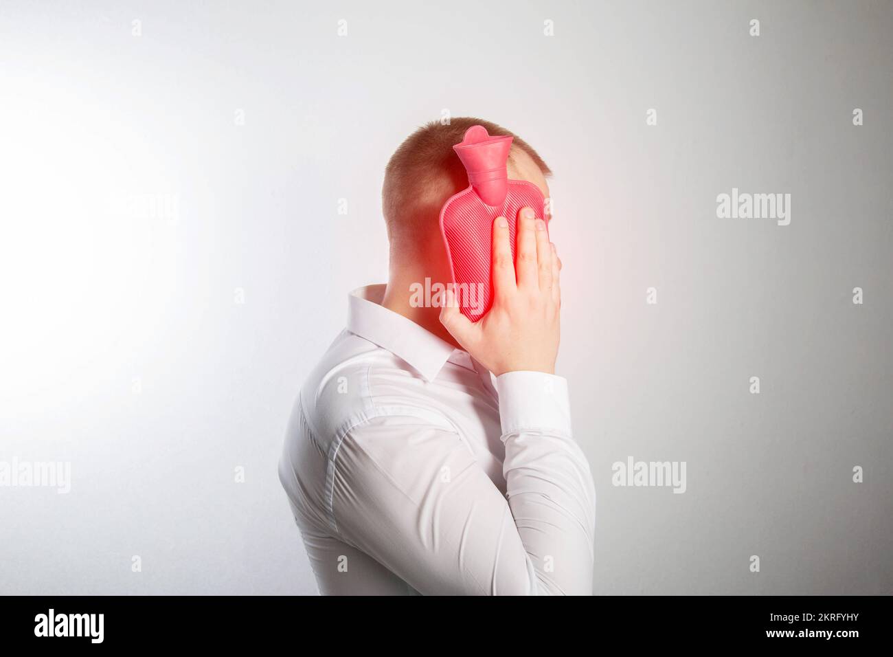 A man holds a heating pad with hot water near his cheek. Toothache