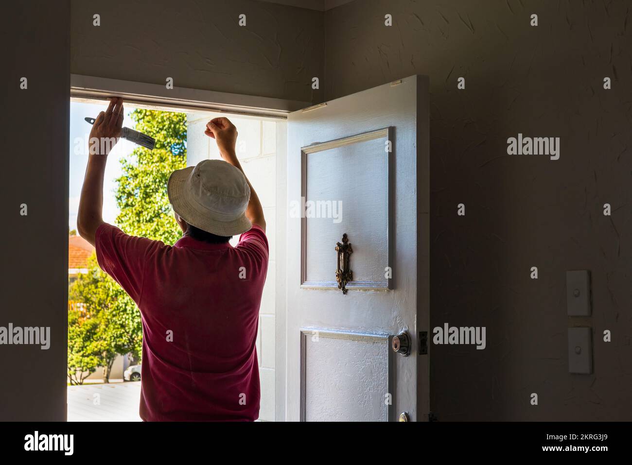 Man applying draught stopping foam tape to the door frame. Home maintenance to meet the healthy home standard. Auckland. Stock Photo