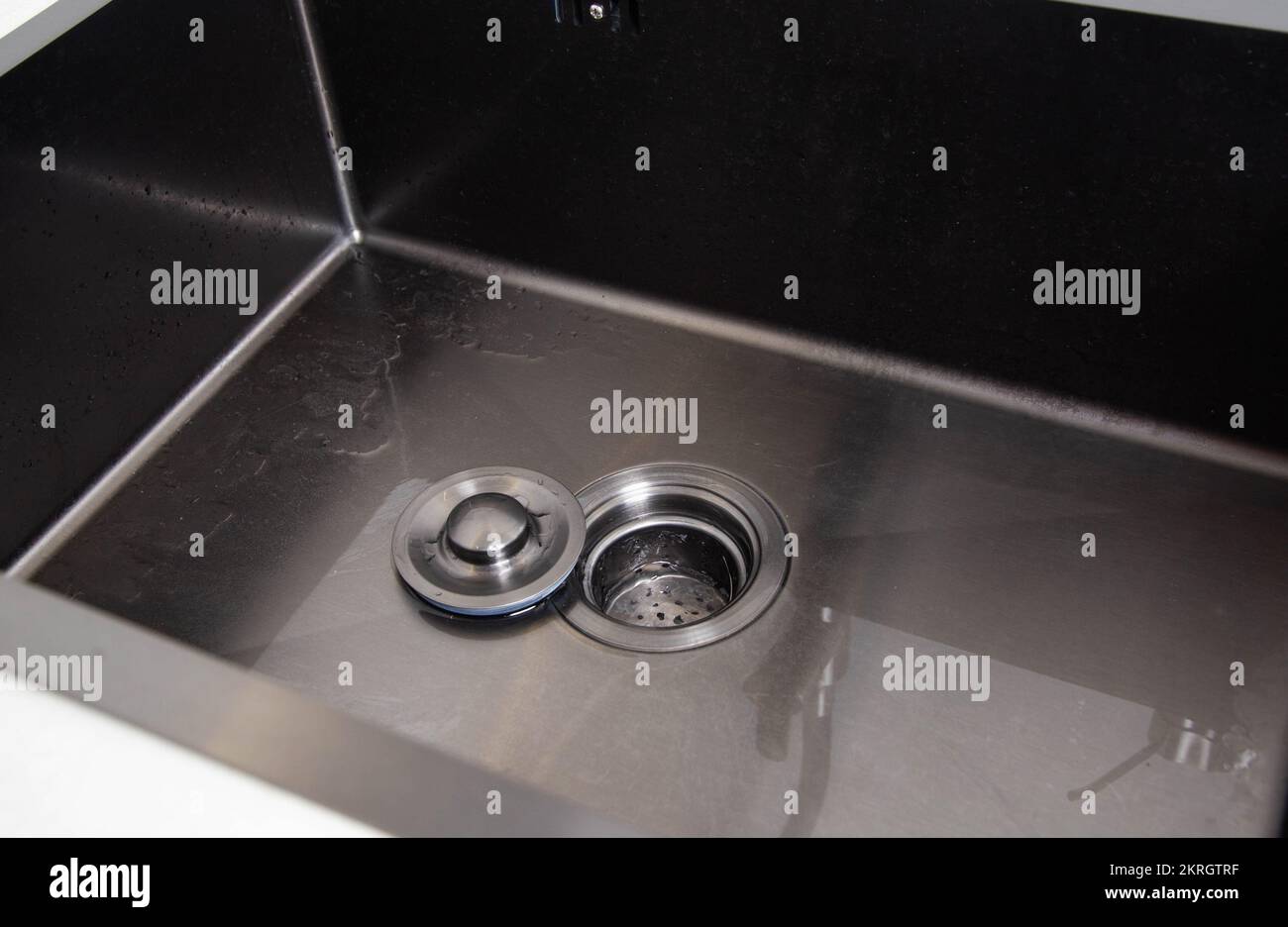 Modern stainless steel sink with drain plug. Water filling. Copy space
