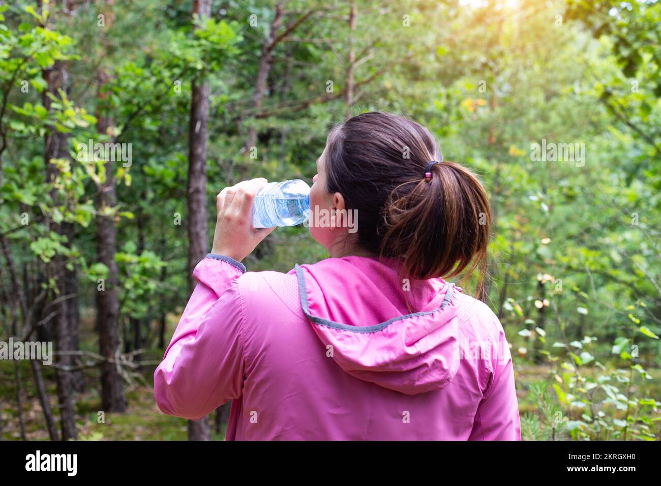The girl drinks water in the forest on a summer sunny day. Survival in the forest, dehydration of the body, mushroomer Stock Photo
